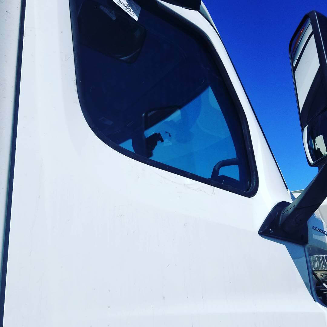 The passenger door of a white semi truck with a new passenger door window