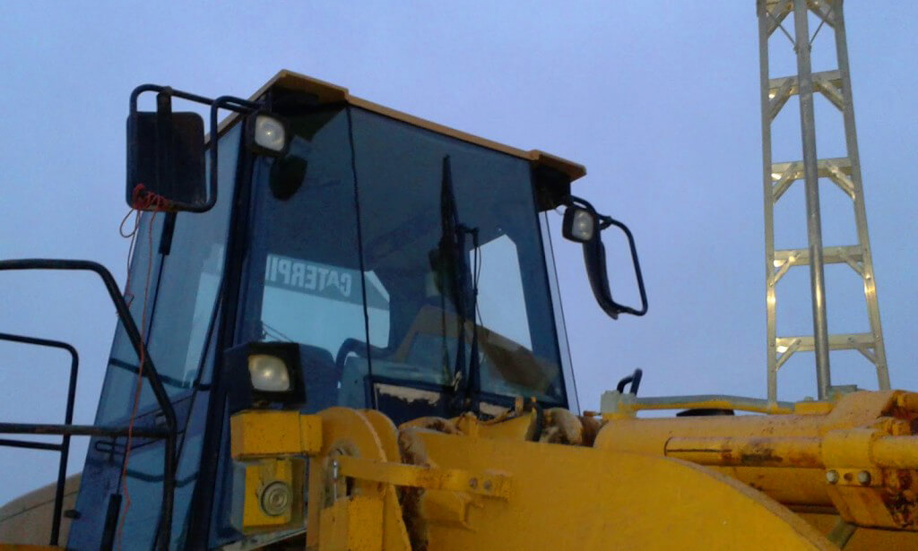 The cabin of a yellow Caterpillar tractor with a new windshield
